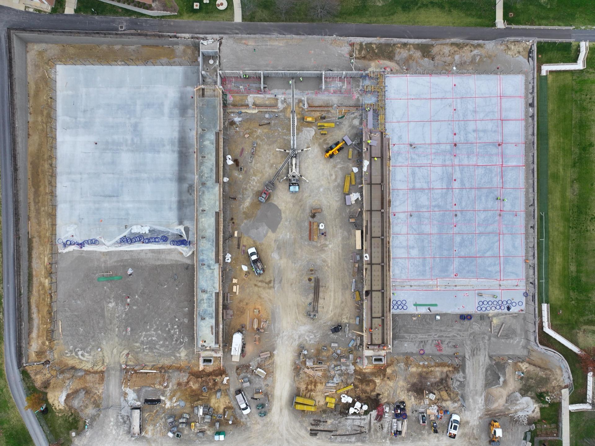 Top-down aerial view of active construction site with foundations and heavy equipment